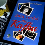 E-Book "Zum Teufel mit Kafka" von Maria Zaffarana, daneben eine Tasse mit der silhouette Franz Kafkas vor den gelben Fassaden Prags